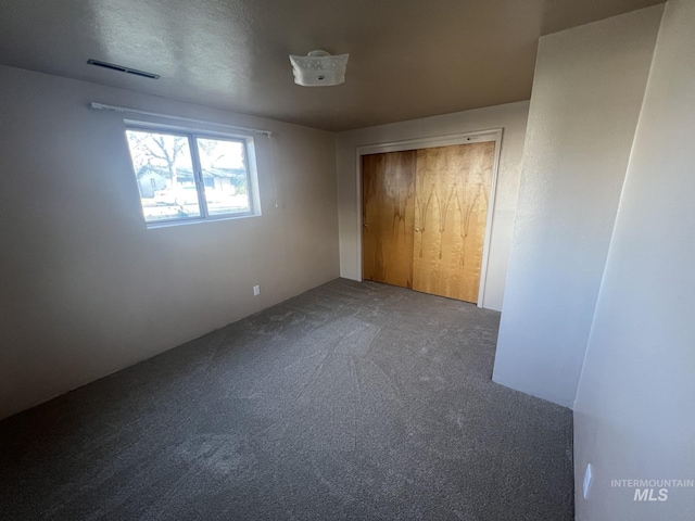 unfurnished bedroom with carpet, a textured ceiling, and a closet