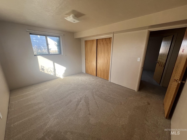 unfurnished bedroom featuring carpet flooring, a textured ceiling, and a closet