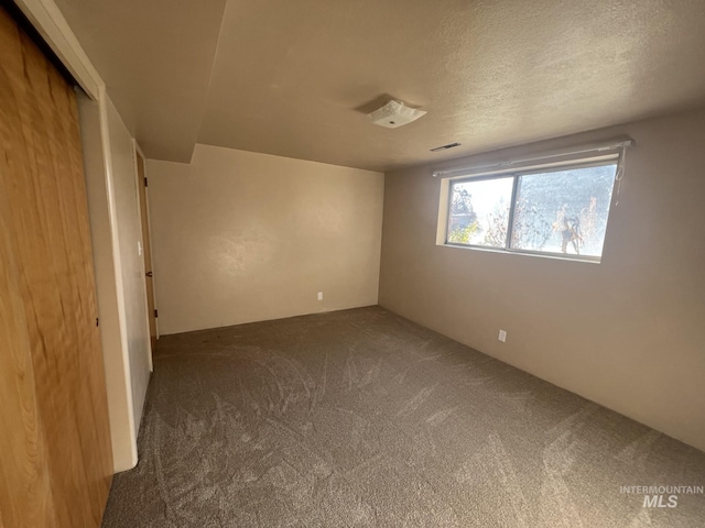 carpeted empty room featuring a textured ceiling