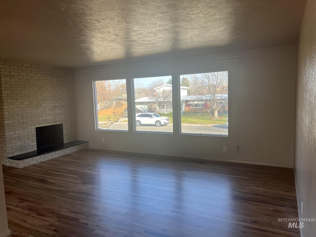 unfurnished living room featuring dark hardwood / wood-style flooring, a fireplace, and plenty of natural light