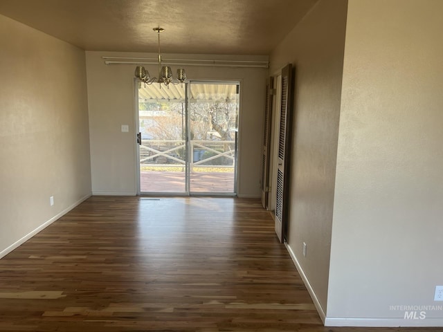 unfurnished dining area with dark hardwood / wood-style floors and an inviting chandelier