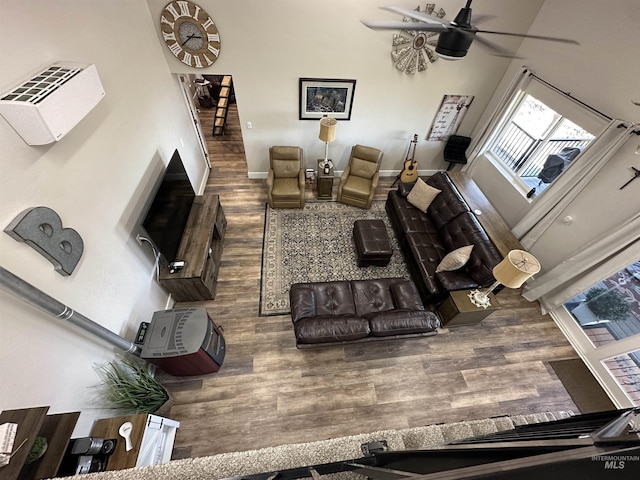 living area with baseboards, ceiling fan, and wood finished floors