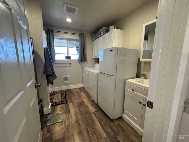 laundry area featuring visible vents, cabinet space, baseboards, dark wood-style floors, and washer and clothes dryer