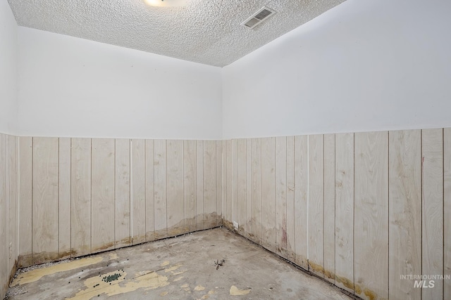 empty room with wooden walls and a textured ceiling