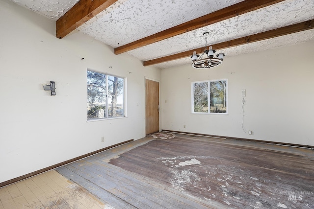 spare room with a wealth of natural light, an inviting chandelier, beamed ceiling, and hardwood / wood-style flooring