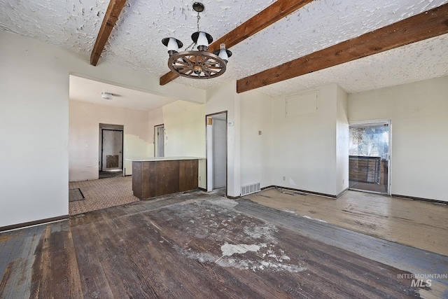 unfurnished living room with ceiling fan, beam ceiling, wood-type flooring, and a textured ceiling