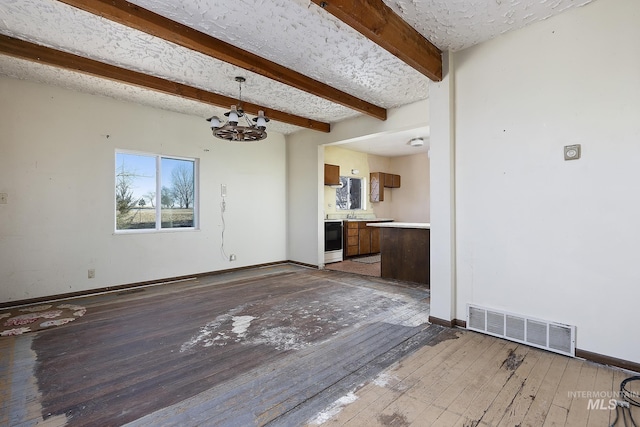 unfurnished living room with beamed ceiling, wood-type flooring, and a notable chandelier