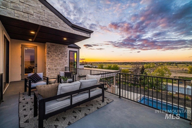 balcony at dusk featuring an outdoor living space