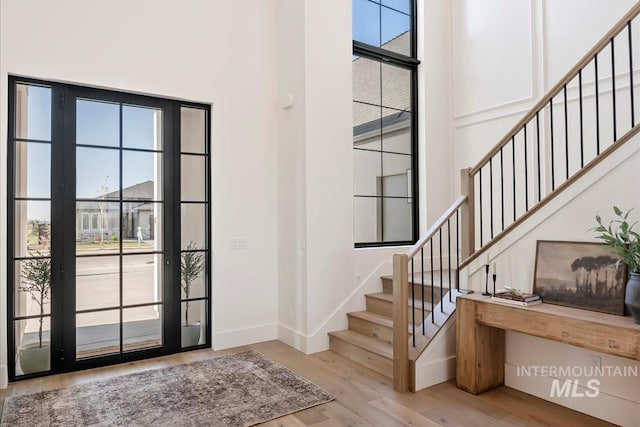 entryway featuring baseboards, wood finished floors, and stairs