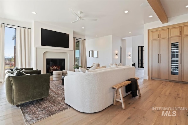 living area with beverage cooler, light wood-style floors, ceiling fan, beamed ceiling, and recessed lighting
