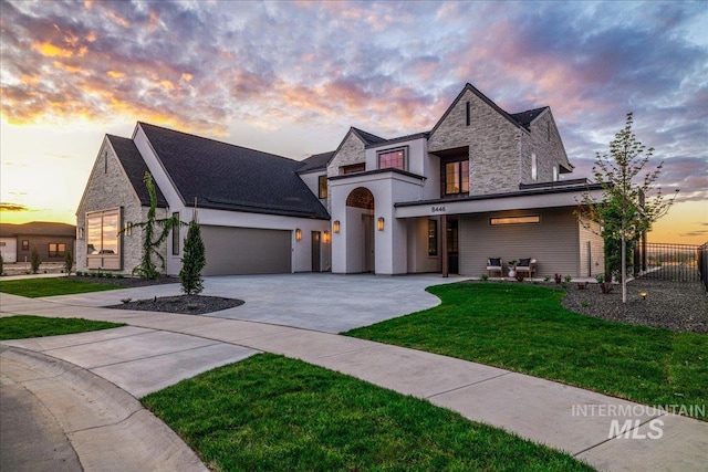 french country inspired facade with fence, a yard, an attached garage, driveway, and stone siding