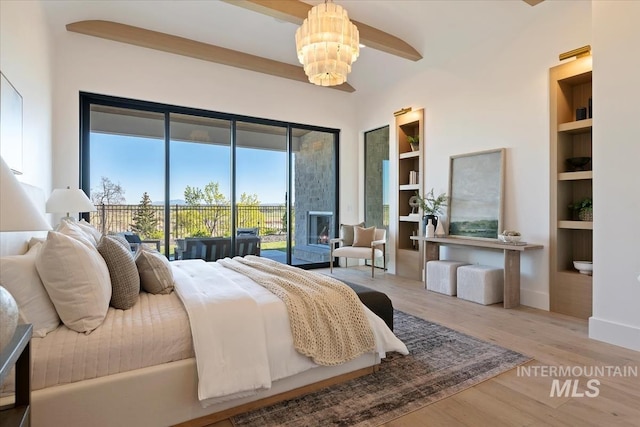 bedroom with baseboards, a notable chandelier, wood finished floors, and access to exterior