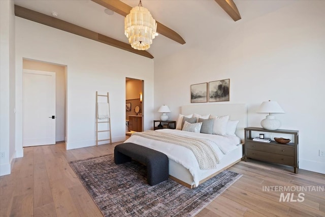 bedroom with beamed ceiling, hardwood / wood-style floors, baseboards, and ensuite bathroom