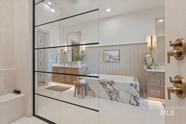 full bath featuring walk in shower, a garden tub, and vanity