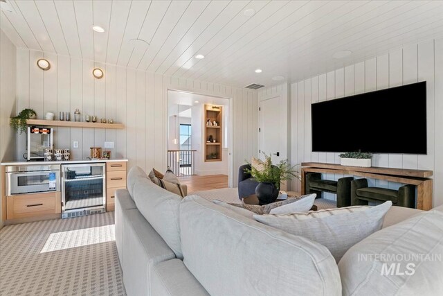 living room featuring light carpet, visible vents, recessed lighting, a bar, and beverage cooler