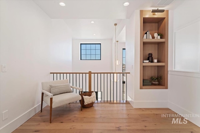 living area featuring baseboards, built in shelves, and light wood-style flooring