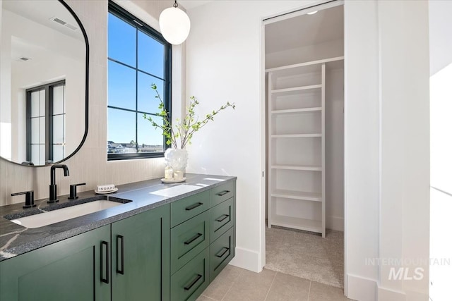 bathroom with a spacious closet, tile patterned floors, vanity, and visible vents