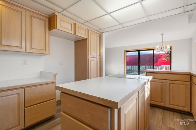 kitchen with a center island, a paneled ceiling, pendant lighting, light hardwood / wood-style flooring, and a chandelier