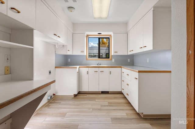 kitchen featuring light hardwood / wood-style flooring, white cabinetry, and sink