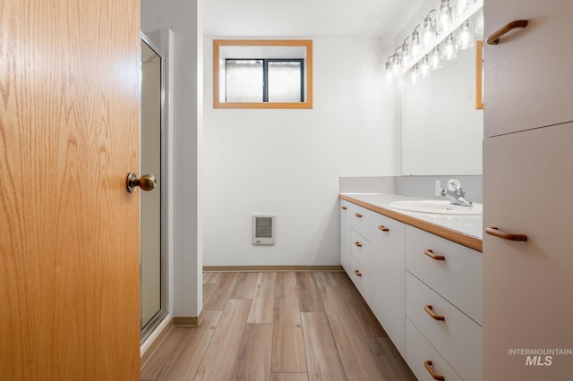 bathroom featuring vanity, wood-type flooring, heating unit, and a shower with door