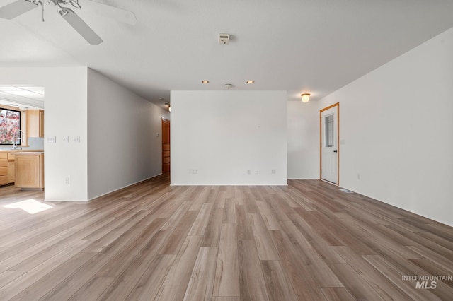 empty room featuring ceiling fan, sink, and light wood-type flooring