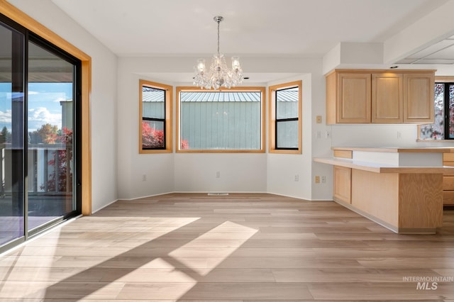 interior space with light hardwood / wood-style floors, light brown cabinets, decorative light fixtures, and an inviting chandelier