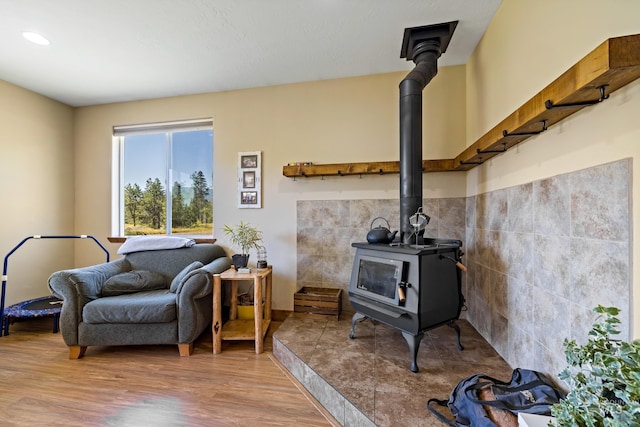 sitting room with a wood stove, tile walls, recessed lighting, and wood finished floors