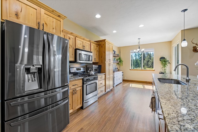 kitchen featuring wood finished floors, a sink, stainless steel appliances, a chandelier, and recessed lighting