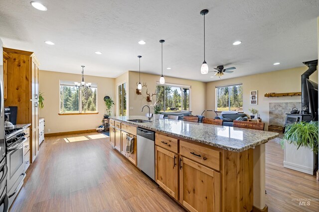 kitchen with a sink, a wood stove, stainless steel appliances, and a healthy amount of sunlight