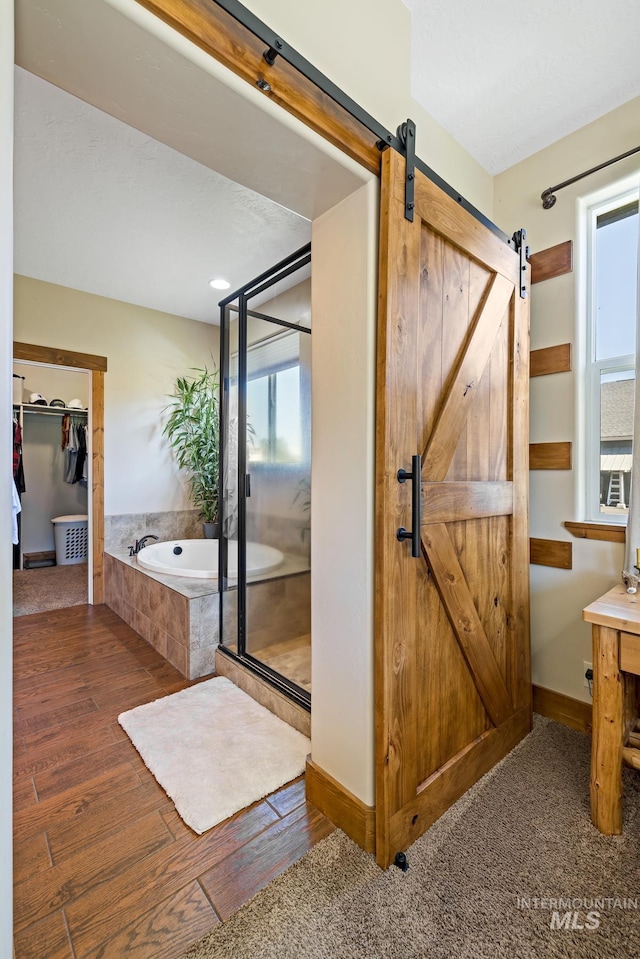 bathroom with an enclosed shower, a bath, baseboards, and wood finished floors