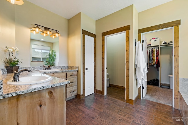 full bath featuring vanity, a spacious closet, baseboards, and wood finished floors