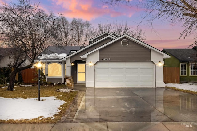 view of front facade featuring concrete driveway, an attached garage, and fence