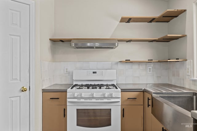 kitchen featuring white range with gas stovetop, wall chimney range hood, stainless steel counters, decorative backsplash, and open shelves