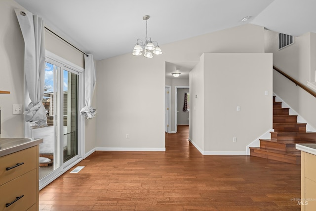 unfurnished dining area featuring lofted ceiling, stairway, light wood-style flooring, and visible vents