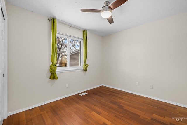 spare room with visible vents, ceiling fan, baseboards, and wood finished floors