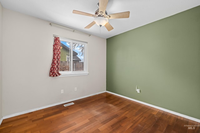 unfurnished room with a ceiling fan, baseboards, visible vents, and wood finished floors