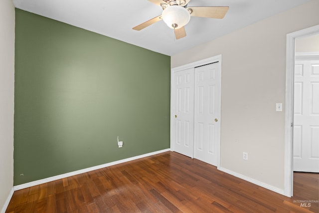 unfurnished bedroom featuring dark wood-style floors, a closet, a ceiling fan, and baseboards