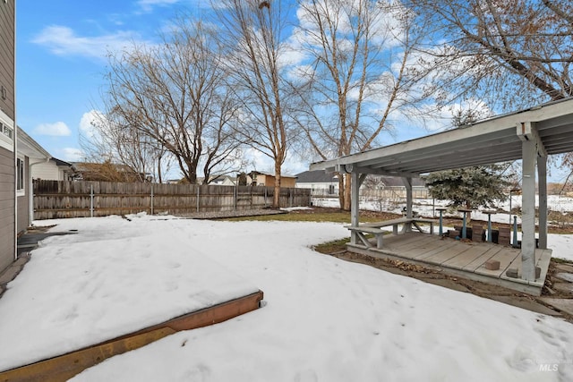 snowy yard featuring fence and a wooden deck