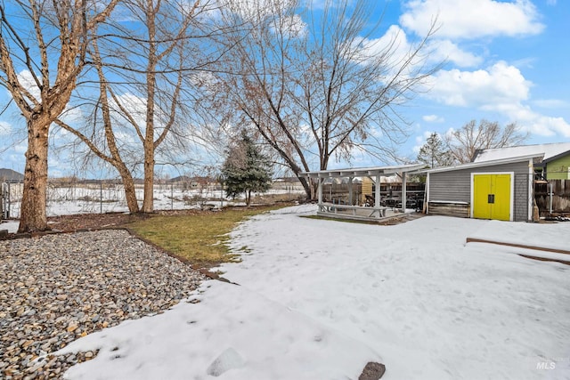 snowy yard featuring an outdoor structure, fence, and a shed