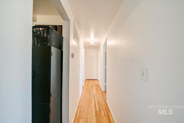 hall with light wood-type flooring, baseboards, and a heating unit