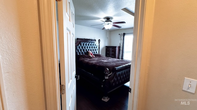 bedroom featuring a textured ceiling, ceiling fan, and a textured wall