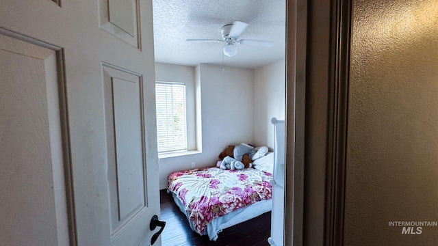 bedroom with dark wood-style flooring, a textured ceiling, and ceiling fan