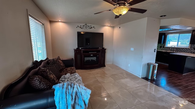 living room featuring ceiling fan and a glass covered fireplace