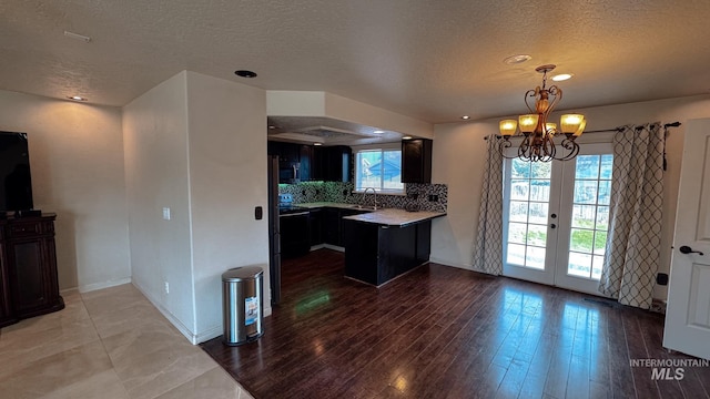 kitchen featuring a peninsula, a textured ceiling, a healthy amount of sunlight, and a sink