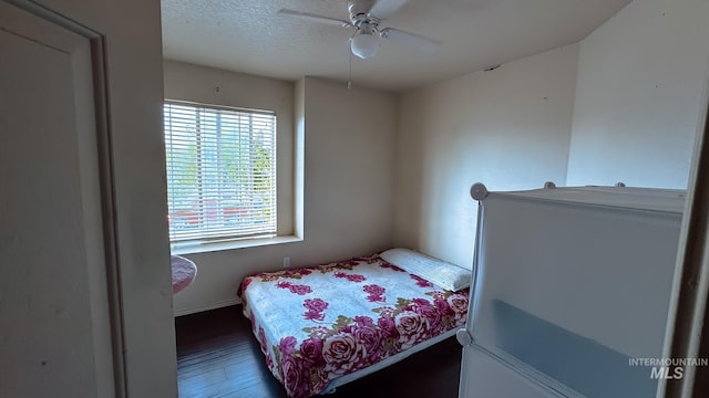 bedroom with ceiling fan, a textured ceiling, baseboards, and wood finished floors
