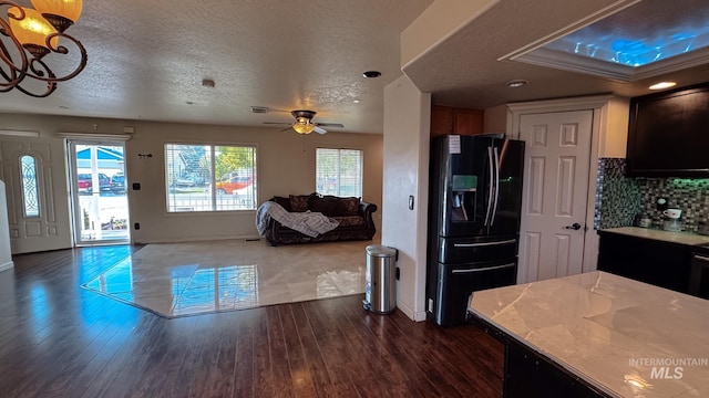 kitchen with ceiling fan with notable chandelier, open floor plan, baseboards, light countertops, and black refrigerator with ice dispenser