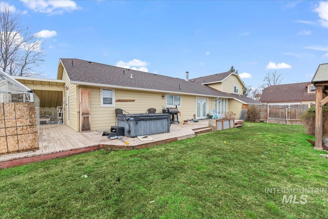 rear view of house featuring fence, a wooden deck, a yard, a shingled roof, and a hot tub