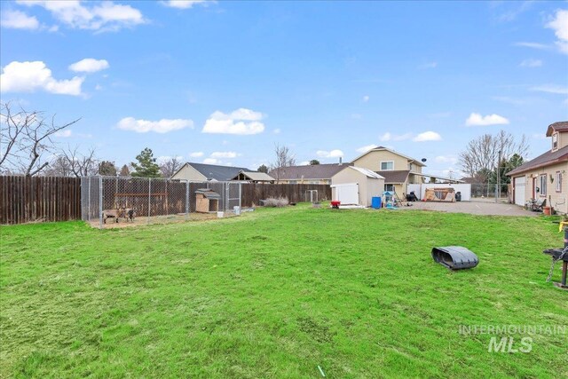 view of yard featuring a storage unit, an outdoor structure, and fence
