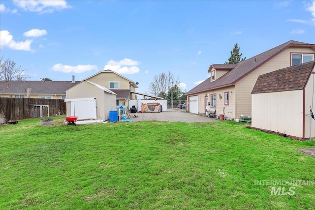 view of yard featuring an outbuilding, a shed, a fenced backyard, a garage, and aphalt driveway
