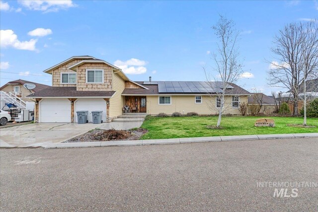 view of front of house with solar panels, a front lawn, concrete driveway, and a garage